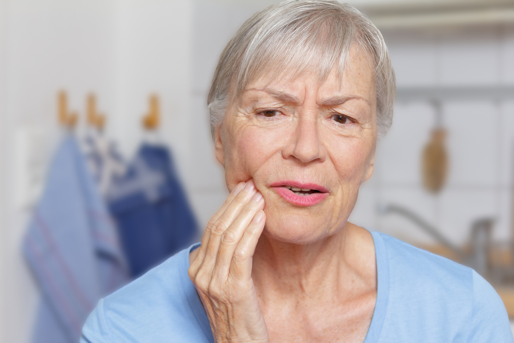 Older woman point to mouth indicating pain